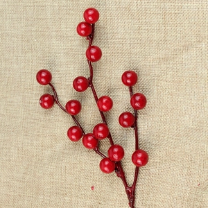 Close-up of lifelike artificial red berry branches on a textured beige linen background