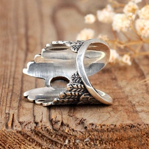 Detail of silver angel wing ring with moonstone on rustic wooden surface with dried flowers