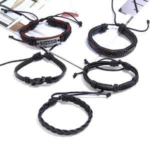 Detail shot of 5-piece braided leather bracelets with engraved Dream metal plate
