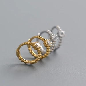 Detailed view of gold and silver beaded hoop earrings with a sparkling round gemstone