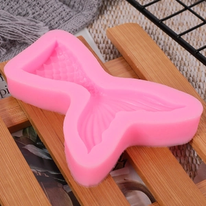 Detail of pink mermaid tail silicone mold for fondant and cake decorating on a wooden stand