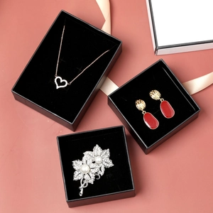 Detailed top view of black jewelry boxes with plush lining on a brick red surface