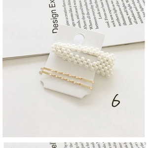 Set of minimalist gold twist barrettes and geometric pearl hair clips on aesthetic paper