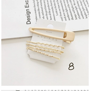 Detail of 5-piece golden pearl hair clip set on display card with magazine background