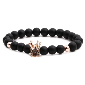 Macro shot of matte black beads and a rose gold crown charm with black zircon stones