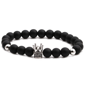 Close-up of matte black stone bead bracelet with a silver crown charm and polished beads