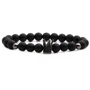 Macro shot of matte black beaded bracelet featuring a silver crown charm with crystals