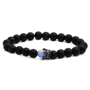 Matte black stone bead bracelet with a blue cat eye stone and crown charms on white background