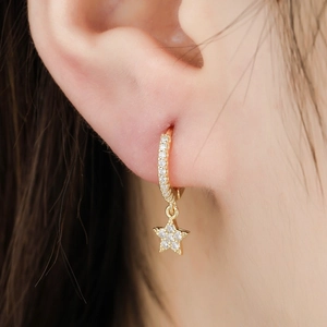 Macro shot of gold star hoop earrings with sparkling crystals worn by a model