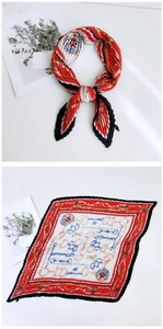Detail of red and white pleated silk scarf featuring golden chains and emblems patterns