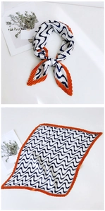 Detail of pleated square silk scarf with blue wave patterns and vibrant orange edges