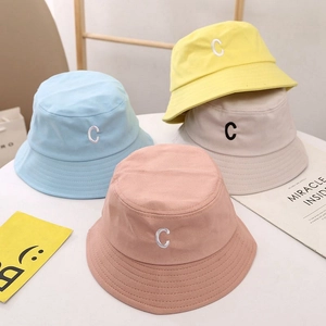 Détail de quatre bobs pour enfants colorés avec broderie C en toile de coton douce