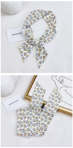 Detail view of long silk scarf with blue and orange feather print in a bow and flat lay