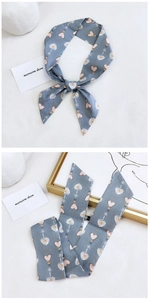 Detail of grey silk scarf with pink heart patterns showing texture and knot styling
