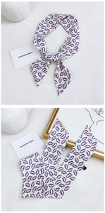 Detailed pattern of patterned long silk scarf tied and folded for styling bags