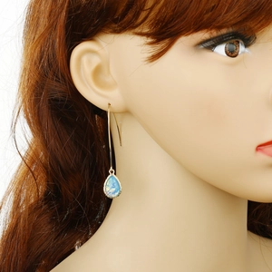 Elegant gold hook earrings with iridescent blue opal teardrop pendants on model