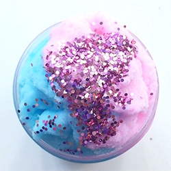 Close-up of pink and blue cloud slime with purple glitters in a clear round container
