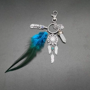 Close-up of bohemian dreamcatcher keychain with teal feathers and Hamsa hand charm
