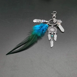 Detail of dream catcher keychain with blue feathers, Hamsa Hand, and evil eye charm