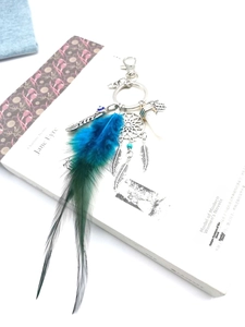 Detail of dreamcatcher keychain with Hamsa Hand and teal feathers on a white book