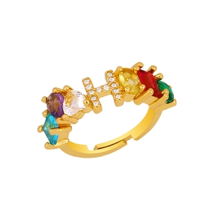 Macro detail of gold adjustable ring featuring crystal letter H and colorful gemstones