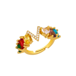 Detail of gold adjustable ring featuring a diamond-set letter V and multi-color gemstones
