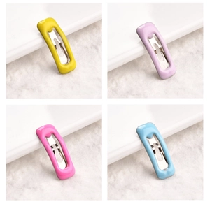 Primo piano di mini fermagli da 2cm nei colori giallo, viola, rosa e blu su fondo morbido