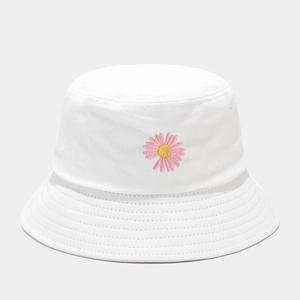 Gros plan d'une broderie de marguerite rose sur un chapeau bob en coton blanc