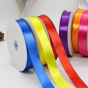 Vibrant 2.5cm satin polyester ribbons in multiple colors on white spools for gift wrapping