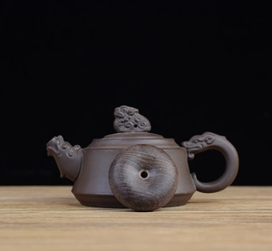 Detailed view of hand-carved dragon patterns on a dark brown Zisha clay teapot