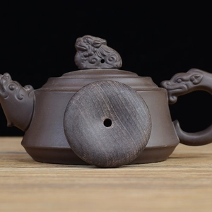 Handcrafted ebony wood teapot with lion lid knob and dragon spout on dark background