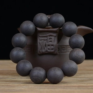 Handcrafted ebony wood beads bracelet displayed on a traditional teapot as a 12-bead set