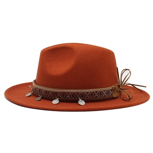 Detail of dark orange wool fedora featuring bohemian woven band and metal coin charms