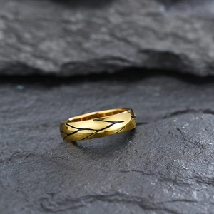 Minimalist gold ring with black cracked texture pattern on a dark slate stone surface