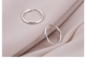 Detailopname van zilveren titanium stalen oorringen op zachte beige stof
