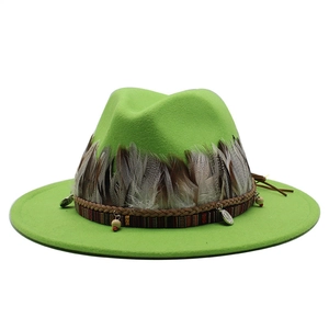 Dettaglio cappello fedora verde brillante con piume a motivi e ciondoli etnici