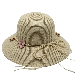 Detailed close-up of straw beach hat with pink 3D flowers and golden bead accents