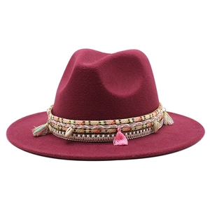 Burgundy wool fedora hat featuring ethnic tassel trim and shell detail on a white background