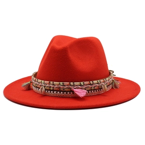 Detail of red wool felt hat with bohemian tassels, woven band, and seashell accents