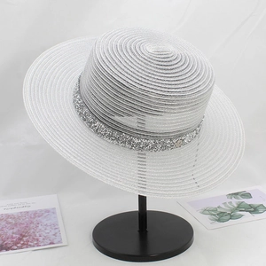 Close-up of white wide brim straw hat with shiny sequin band on a display stand