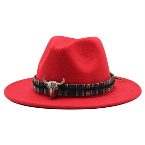 Detail of red wool fedora hat featuring ethnic woven band and metal bull head ornament
