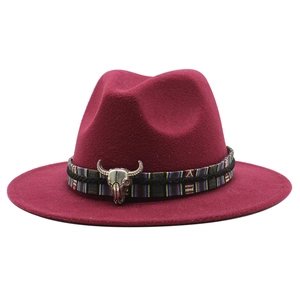 Detail of deep red wool fedora featuring ethnic woven band and silver bull skull ornament