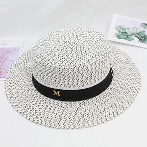 Detail of wide brim straw hat with black grosgrain ribbon and golden metal M letter
