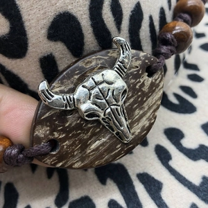 Detailed close-up of a boho woven bracelet featuring a vintage silver cow skull and wood beads