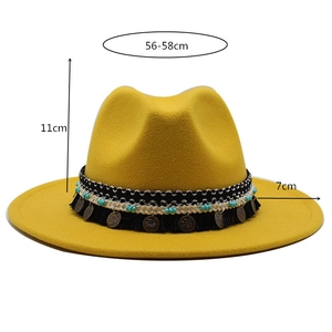Dettaglio cappello in feltro giallo con fascia etnica di perline e nappe decorative