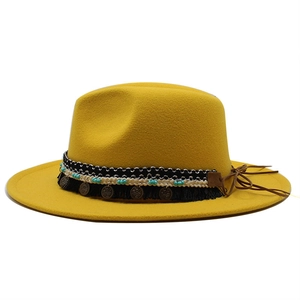 Dettaglio del cappello fedora in lana gialla con nappe e fascia decorata con perline
