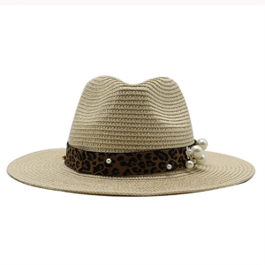 Detail of straw sun hat featuring leopard print ribbon and elegant pearl embellishments