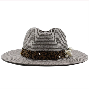 Detail of white straw fedora hat featuring leopard ribbon with pearl and floral accents