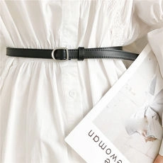Detail of slim black leather belt with silver buckle on white dress for women