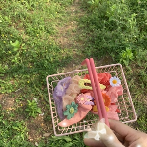 Pink mini metal wire basket filled with colorful fabric scrunchies and hair clips